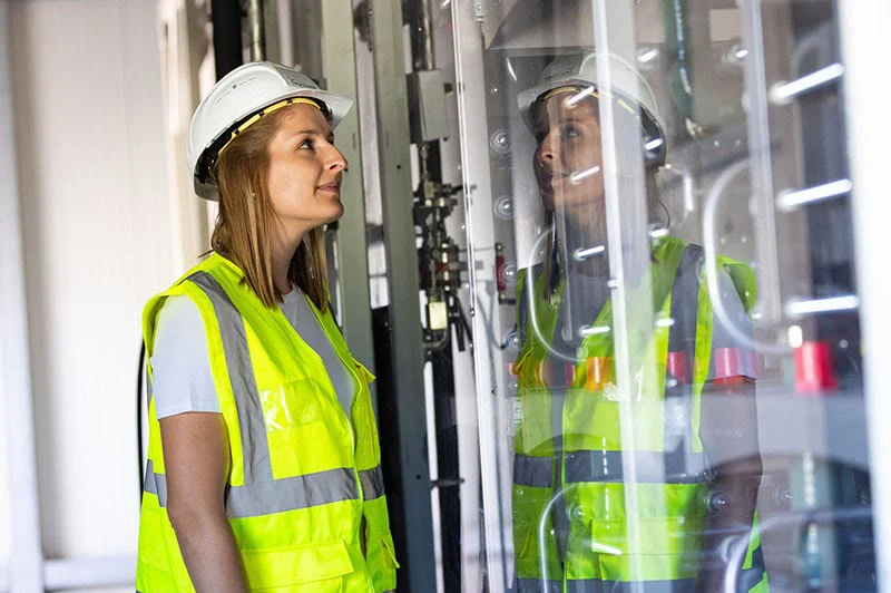 Frau in gelber Weste vor dem Elektrolyseur